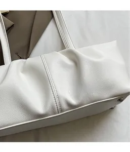Detailansicht der weißen Falten-Tote-Bag mit feiner Litschi-Körnung und Metallnieten am Boden