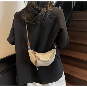 Détail du sac croissant beige avec chaîne argentée, perles et bandoulière en cuir brun