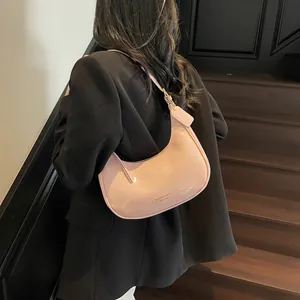 Sac selle demi-lune en cuir verni rose pour femme porté en bandoulière de façon élégante