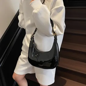 Sac hobo noir en cuir verni brillant avec bandoulière réglable et détails dorés