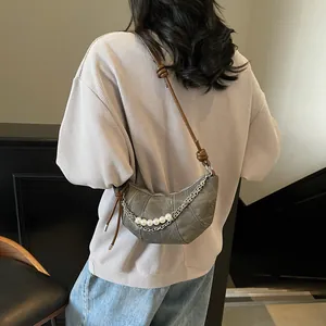 Sac croissant gris avec chaîne argentée et perles porté par un mannequin en style décontracté