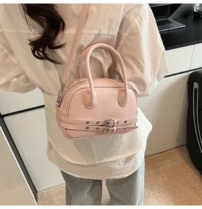 Détail d'un mini sac à main rose clair avec ceintures décoratives et boucles en métal