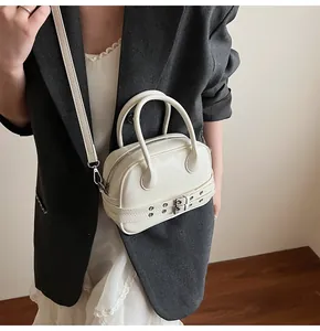 Détail de la boucle en métal argenté et des sangles sur le sac à main en cuir blanc
