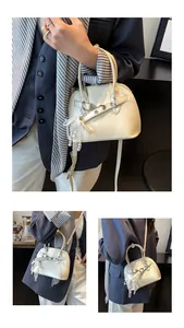 Détail du sac coquillage crème avec boucle en métal argenté et pendentif en dentelle perlée