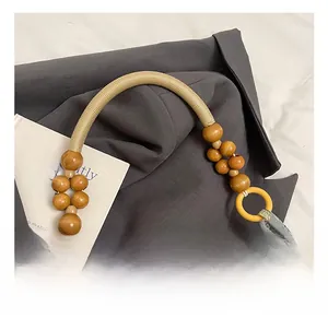 Detail of woven rope handle with brown wooden beads and bird pattern fabric on handbag