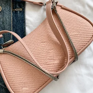 Top view of pink crossbody bag showing woven texture, silver chain, and zip closure