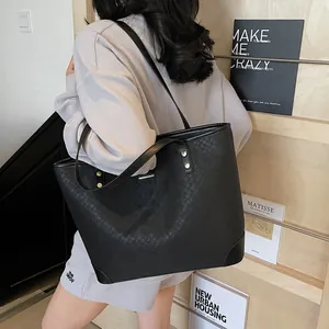 Large black woven leather tote bag with gold rivets and spacious design for daily commute