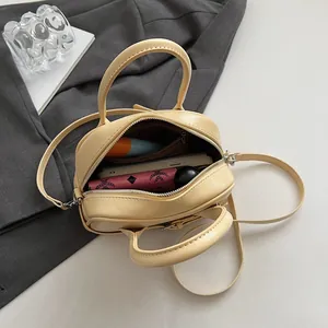 Sac bandoulière beige chic montrant l'intérieur spacieux avec téléphone et portefeuille