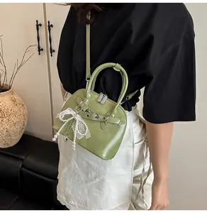 Vue détaillée du sac coquillage vert avocat avec nœud en dentelle et pendentif perle
