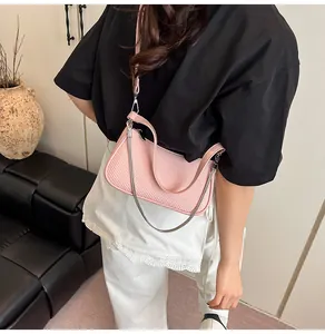 Pink woven shoulder bag with silver chain worn by a model in a modern interior