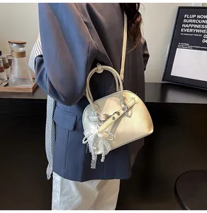 Détail d'un sac à main crème avec pendentif en perles de dentelle et bandoulière amovible