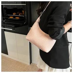 Detail der rosa plissierten Umhängetasche an einem Modell in einer modernen Küche