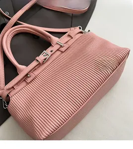 Macro detail of pink pleated faux leather bag with adjustable strap and silver buckles
