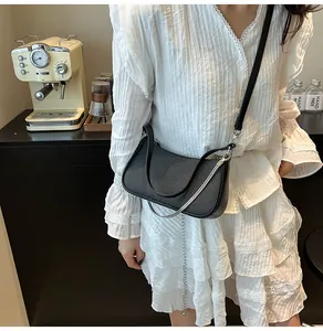 Close-up of black crescent shoulder bag with silver chain detail and woven texture
