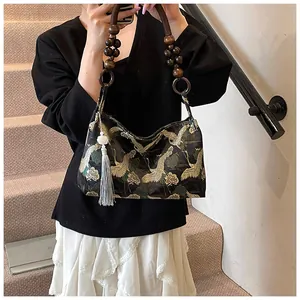 Detail of square shoulder bag with golden crane embroidery and wooden bead handle