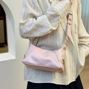Pink PU leather crossbody bag with silver zippers and wide shoulder strap on model