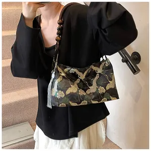 Close-up of embroidered crane and pine patterns on a retro fabric shoulder bag