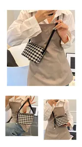 Close-up of black and white checkered canvas shoulder bag with slim strap and zipper
