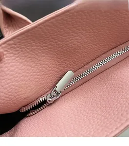 Close-up of a smooth silver metal zipper on a pink lychee-patterned leather handbag