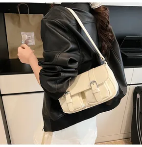 Vue détaillée du sac bandoulière crème avec boucles sur une veste en cuir noir