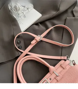 Close-up of pink textured leather handbag with silver hardware and adjustable strap