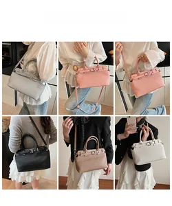 Detail view of stylish pleated handbag with metal buckle strap and detachable shoulder strap
