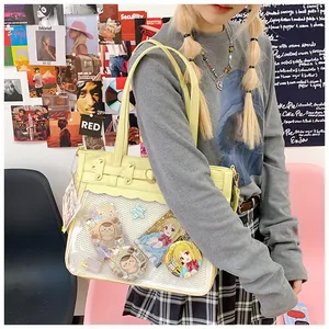 Detalle de un bolso ita beige con ventana transparente, pines anime y hebilla corazón