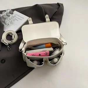 Sac bandoulière minimaliste en cuir beige montrant un rangement interne spacieux