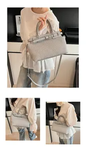 Detail view of grey pleated handbag showing vertical texture and removable shoulder strap