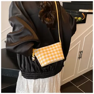 Detail of yellow checkered tote bag showing heart embroidery and woven rope zipper pull