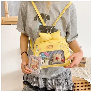 Macro detail of yellow ita bag with bow and transparent window showing plush toys
