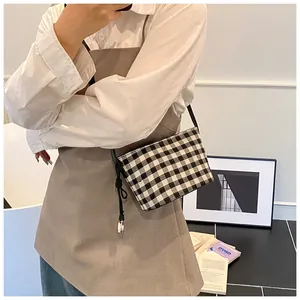 Detail of checkered shoulder bag with knot decoration and silver bead on model