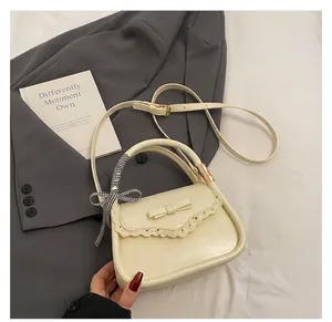 Detail of cream white handbag with lace edge, bow decoration, and ribbon handle