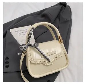Close-up of beige PU leather handbag with lace trim, bow, and ribbon wrapped handle