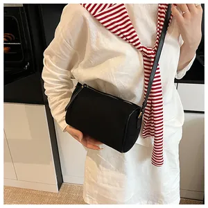 Close-up of a minimalist black cylinder crossbody bag worn with a casual outfit