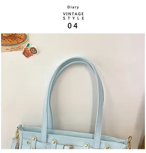 Detalle de bolso tote vintage azul claro con remaches de corazón dorados y correas de cuero