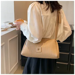 Dettaglio della borsa a tracolla beige a pieghe con texture verticali e fibbia quadrata