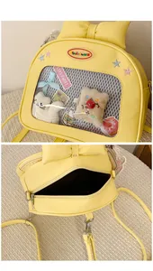 Detail view of yellow Ita bag showing PVC window with cute cat plush and bow accent