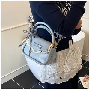 Detailed close-up of light blue handbag with bow ornament and lace trim details