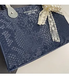 Detail of navy blue faux snakeskin texture with pearl lace charm and silver hardware