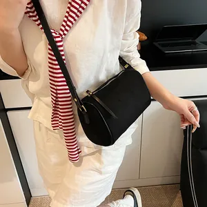 Minimalist black cylinder crossbody bag in matte finish styled with chic white outfit