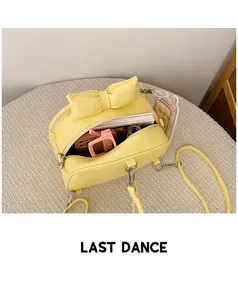 Detail showing the internal storage capacity of a yellow bow crossbody bag with daily items
