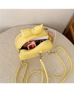 Detail showing the internal storage capacity of a yellow bow crossbody bag with daily items