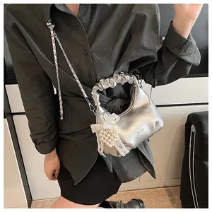Detail of silver metallic pleated bag with pearl heart bow charm and chain strap