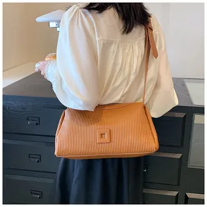 Dettaglio della pelle a pieghe caramello e fibbia sulla borsa a tracolla dal design minimale