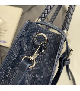 Detailed macro view of dark blue snakeskin texture with woven handle and silver hardware