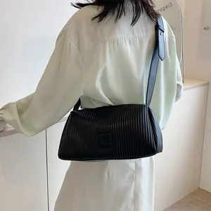 Borsa a cuscino nera plissettata minimalista con logo e tracolla indossata da modella