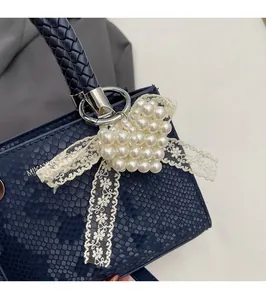 Detail of dark blue snake pattern handbag with heart pearl charm and lace decor
