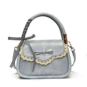 Elegant light blue crossbody bag with lace trim and decorative bow on white background