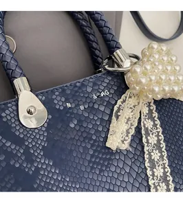 Detailed view of blue snakeskin texture with pearl heart charm and lace bow accessory